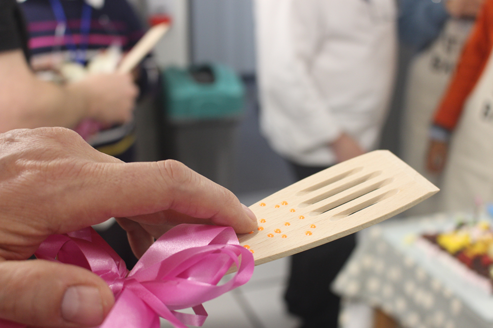 close up of a finger reading braille on a wooden spatula