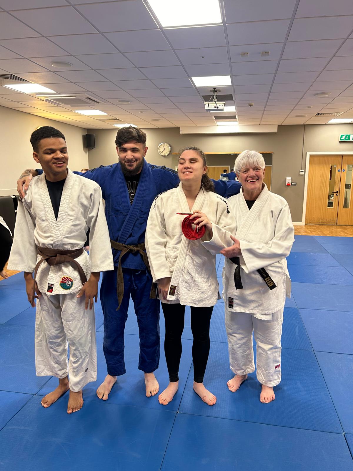 4 people in a fitness studio surrounded by crash mats. They all wear Judo kit