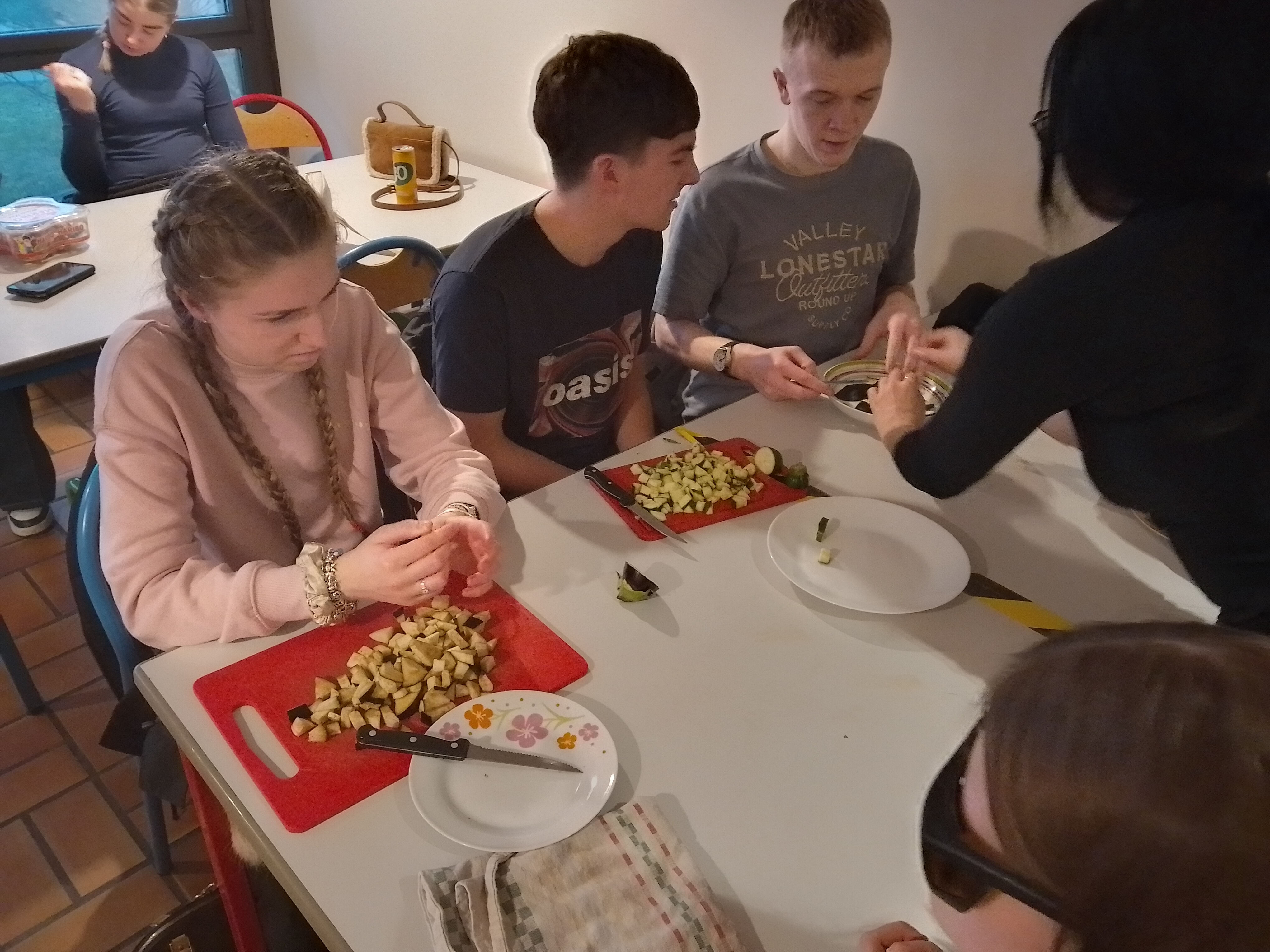 3 RNC Students with chopping boards and knives in front of them.They have just chopped aubergine and courgettes which is lying diced on the boards 