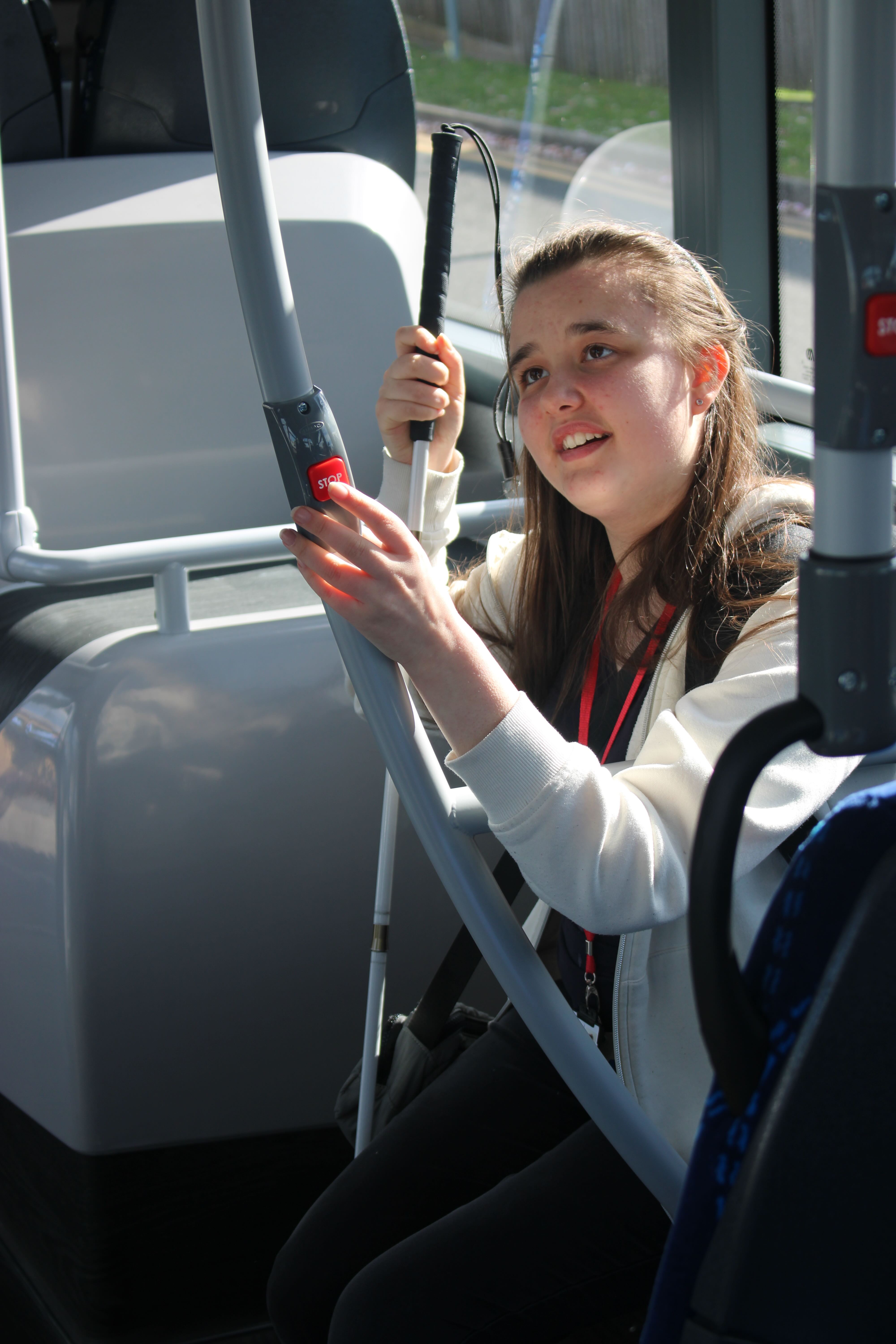 Emily seated on the bus and pressing the big red stop button