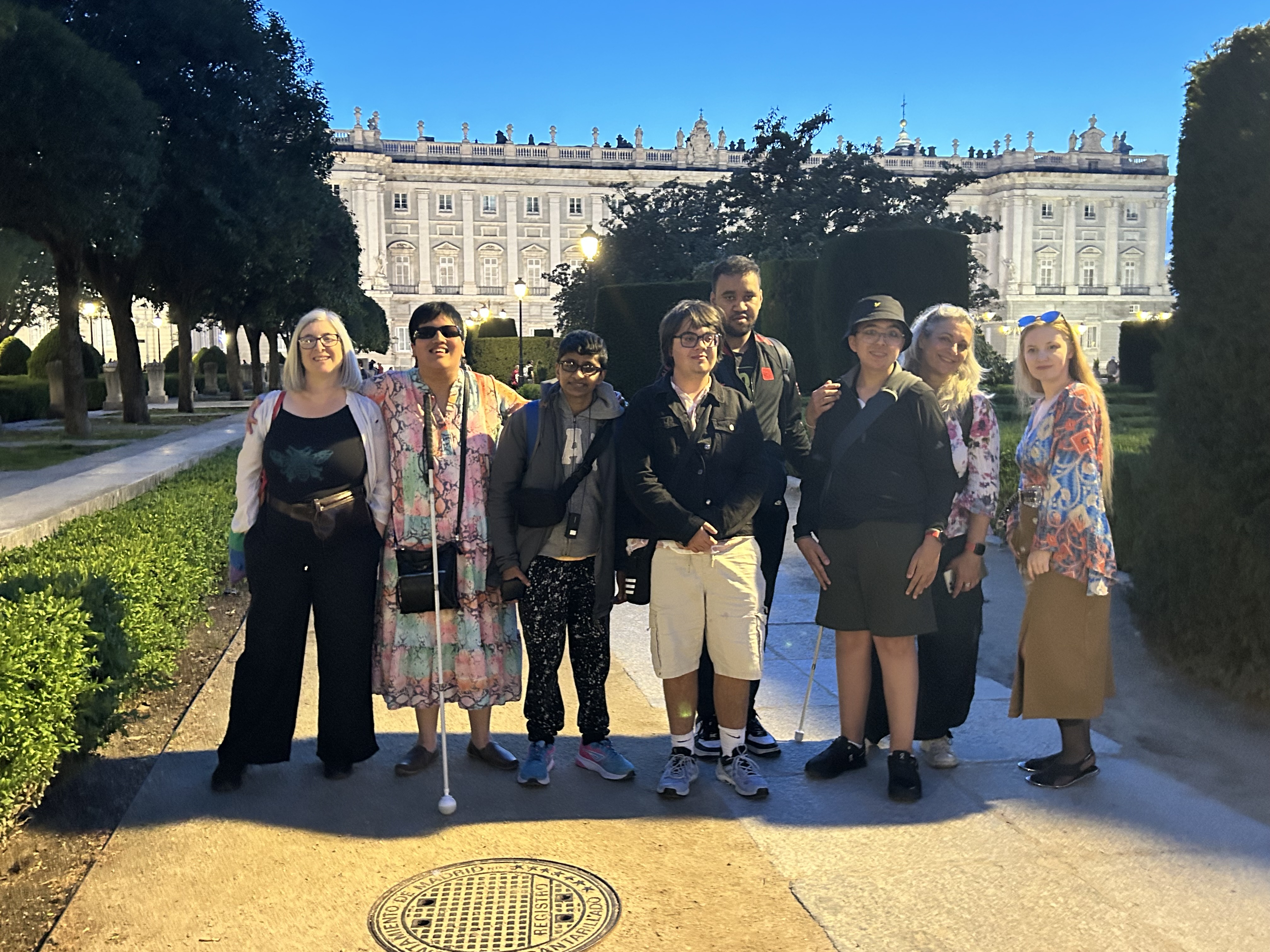 a group of 8 staff and students standing in the gardens of the Royal Palace which can be seen behind them