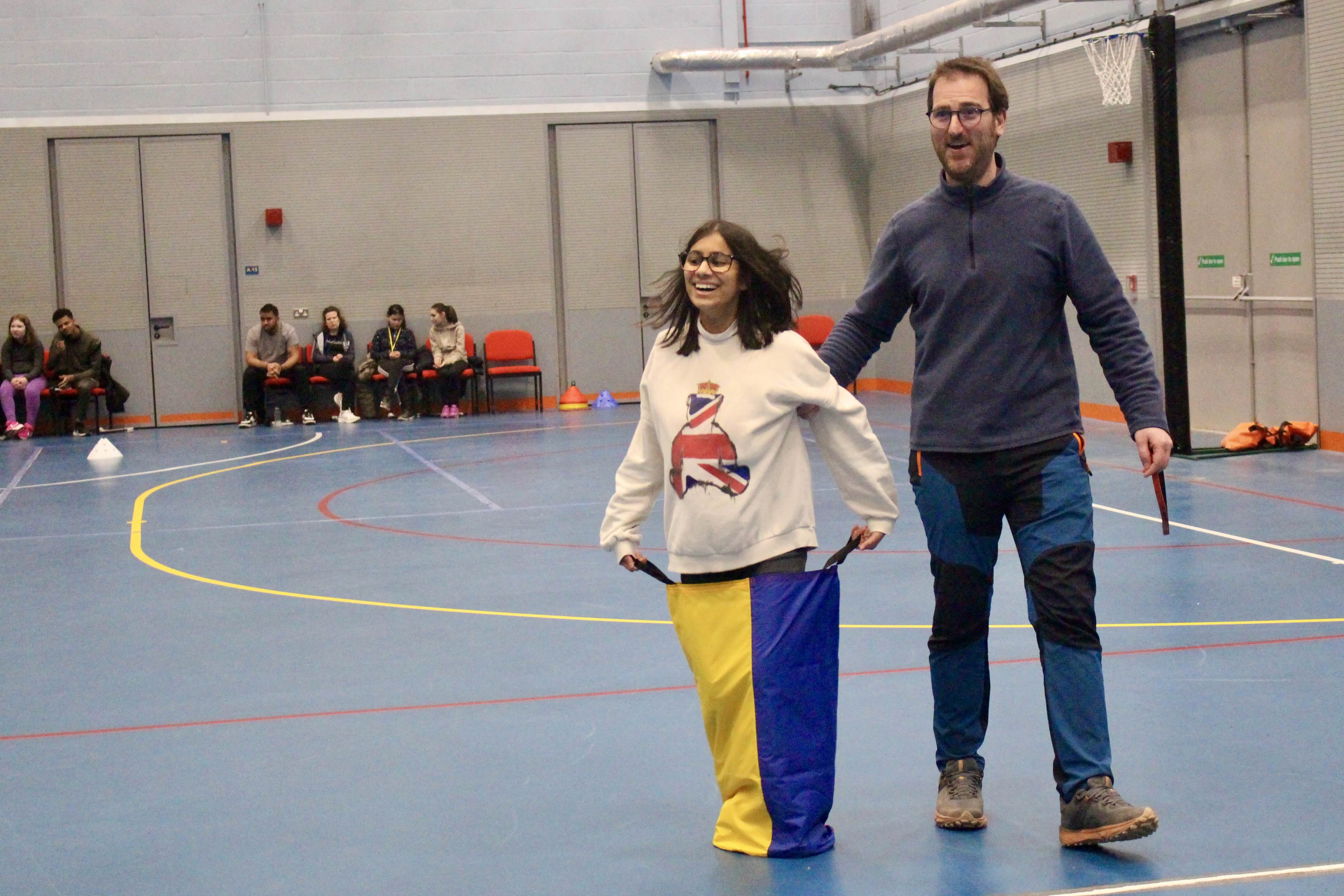 a female student enjoying the sack race - a member of staff is to her left for support