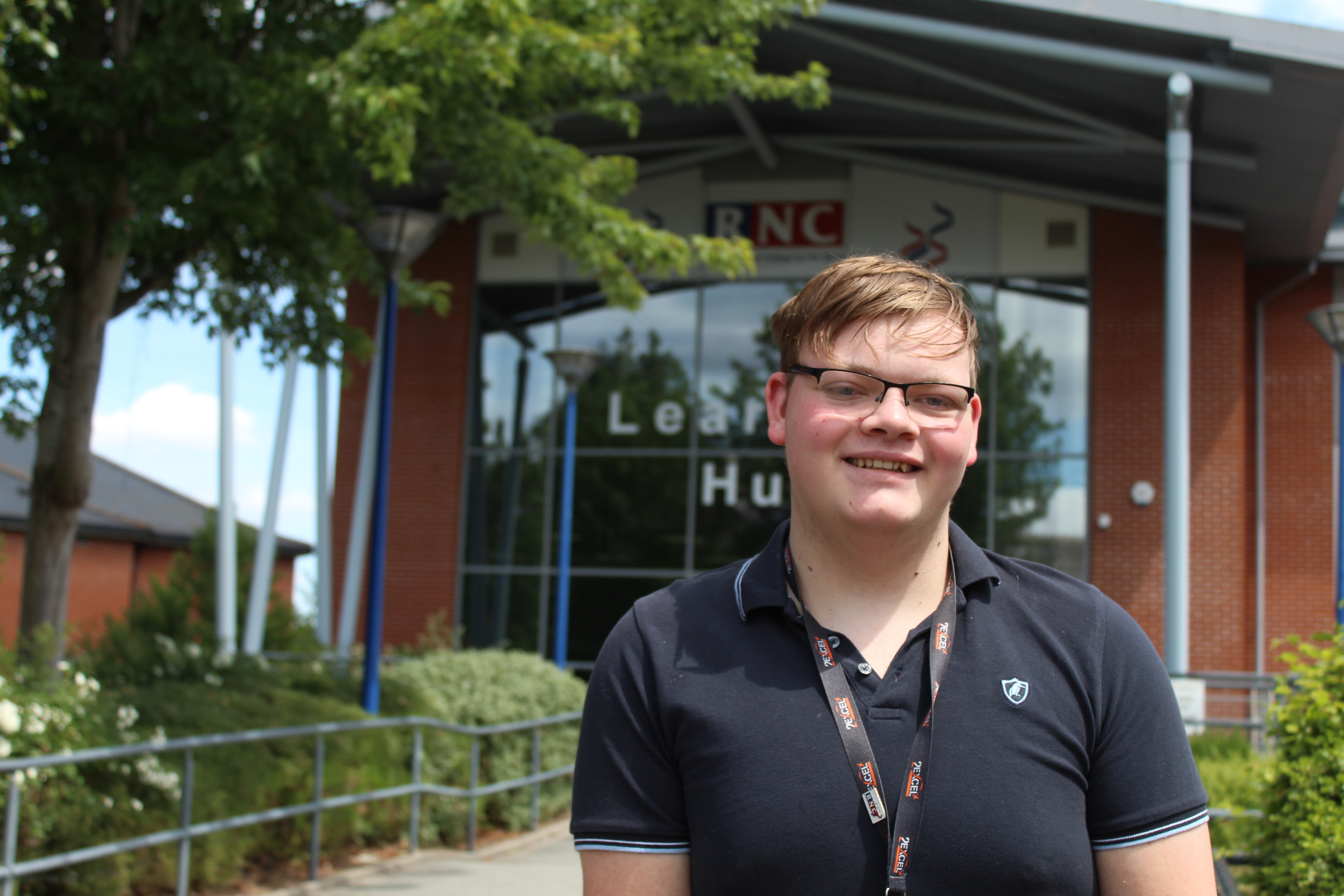 Harvey standing in front of the College at the entrance to the Learning Hub