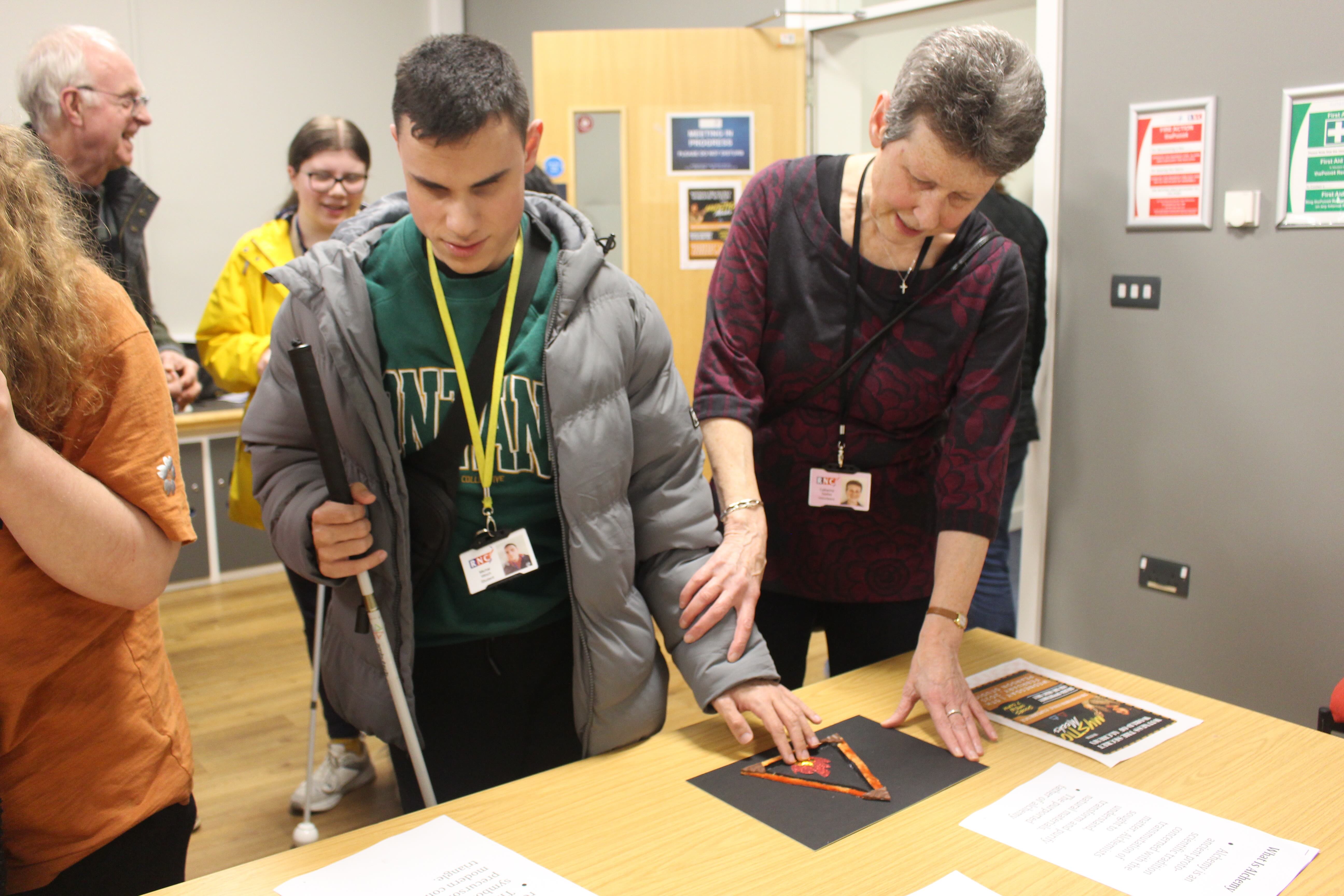 A student and volunteer guide exploring the art piece 'fire' through touch