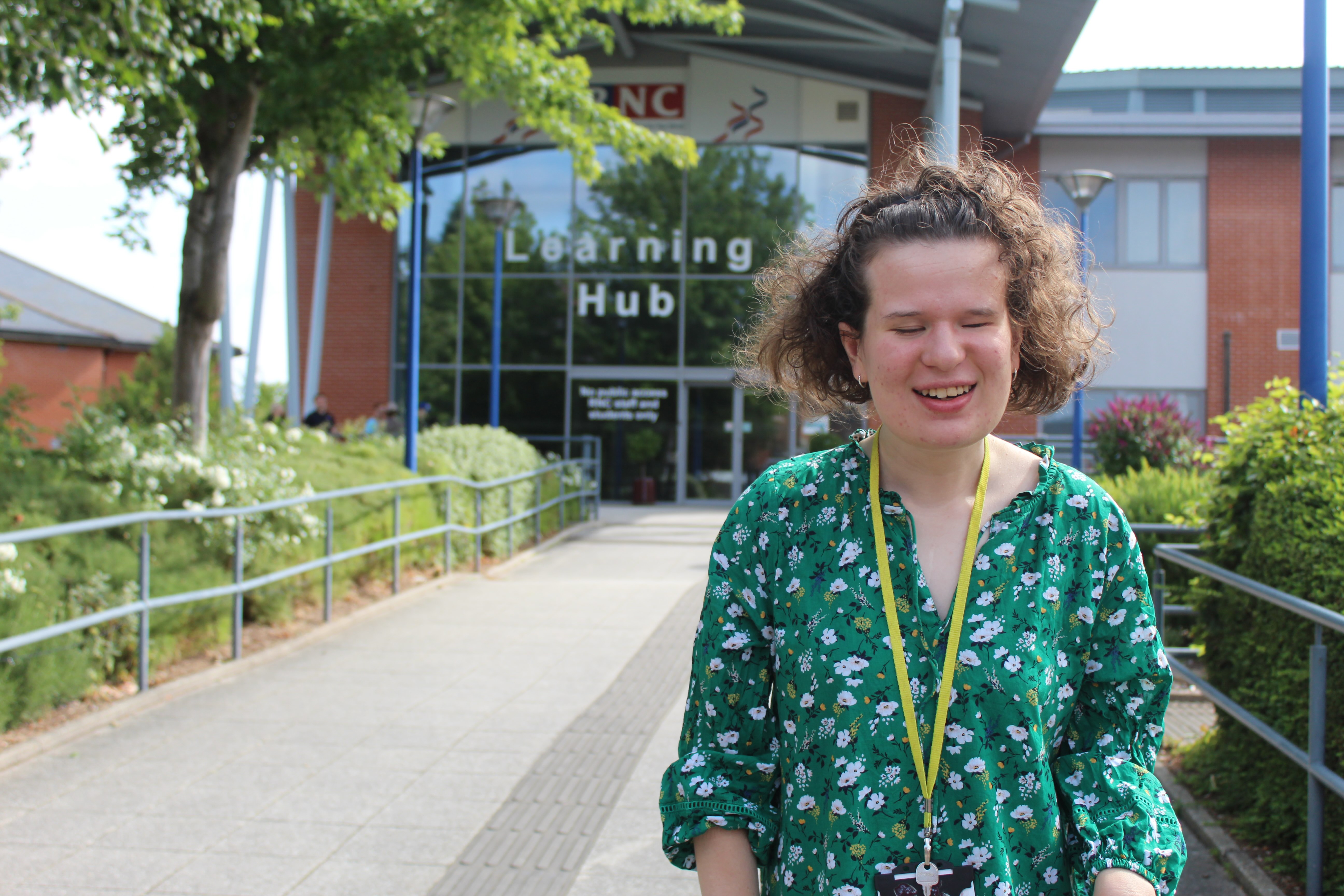 Amy standing and smiling in front of the College's Learning Hub building