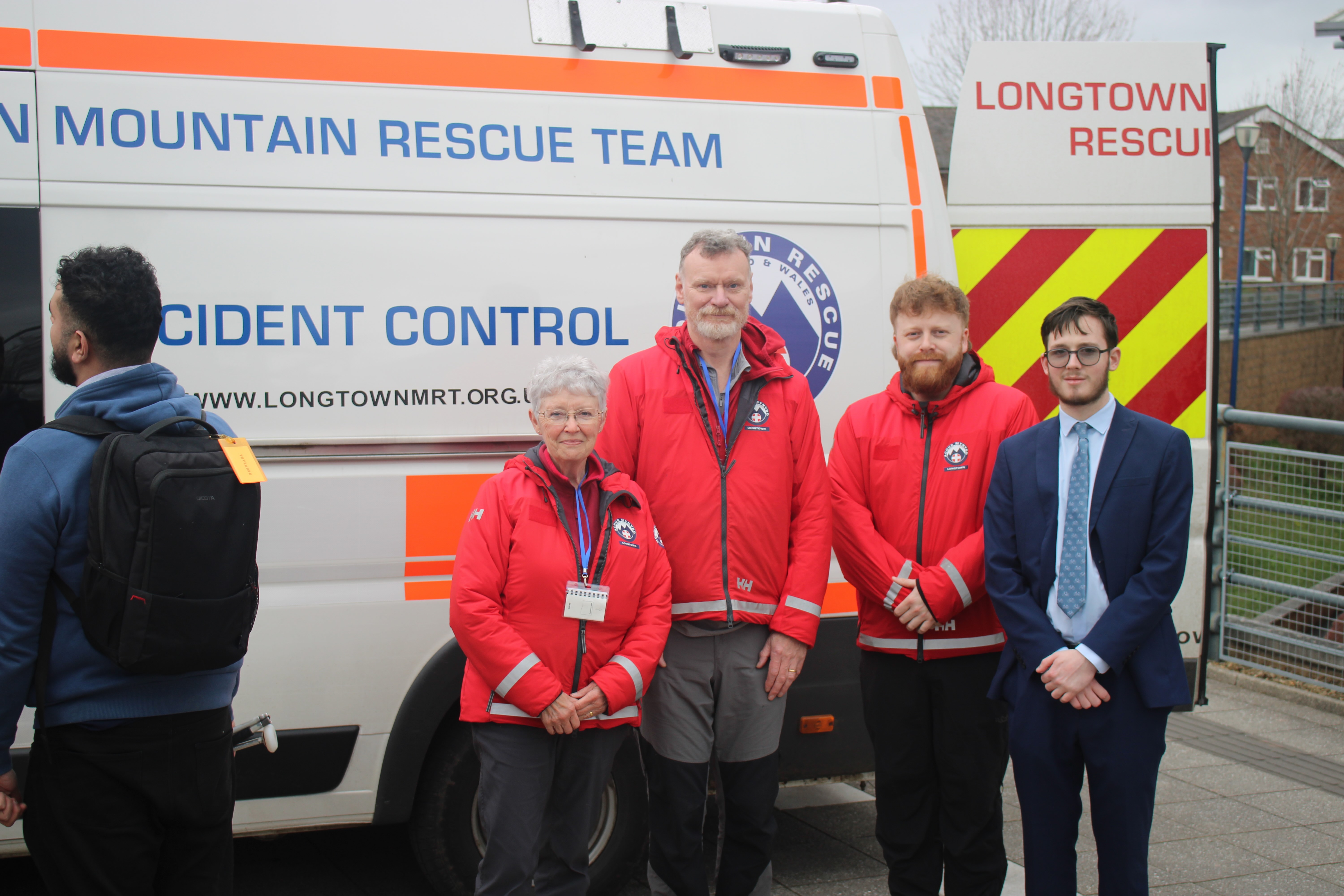 Elliot stands with three members of the Longtown Mountain rescue in front of their vehicle