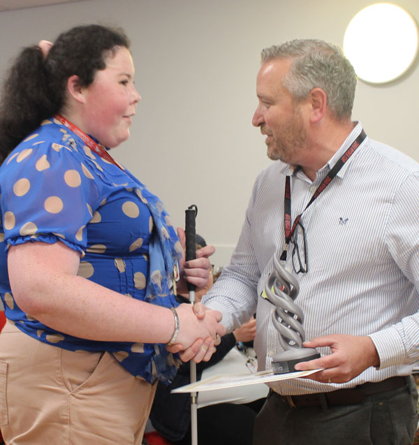 A student shakes hands with a member of staff as she receives her award