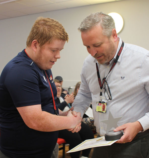 A student being handed an award from a member of staff