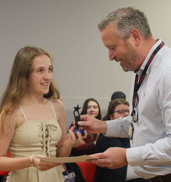 A student receiving a certificate and an award from a member of staff