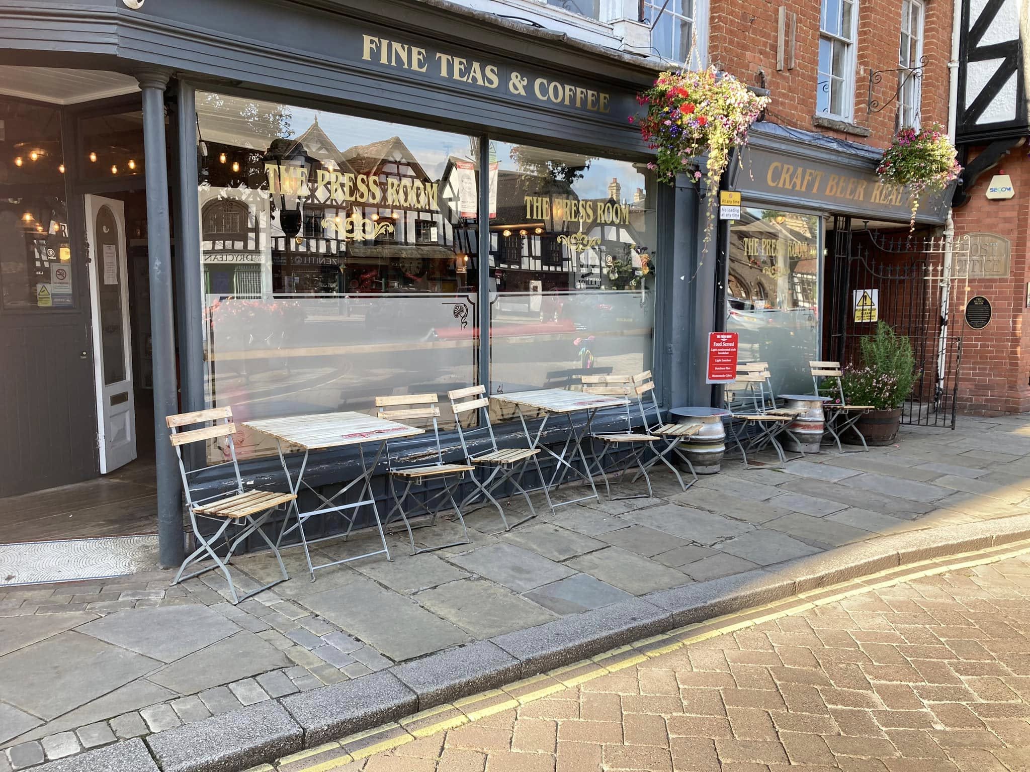 The Press Room bar frontage with large glass windows and bistro chairs and tables outside on the pavement