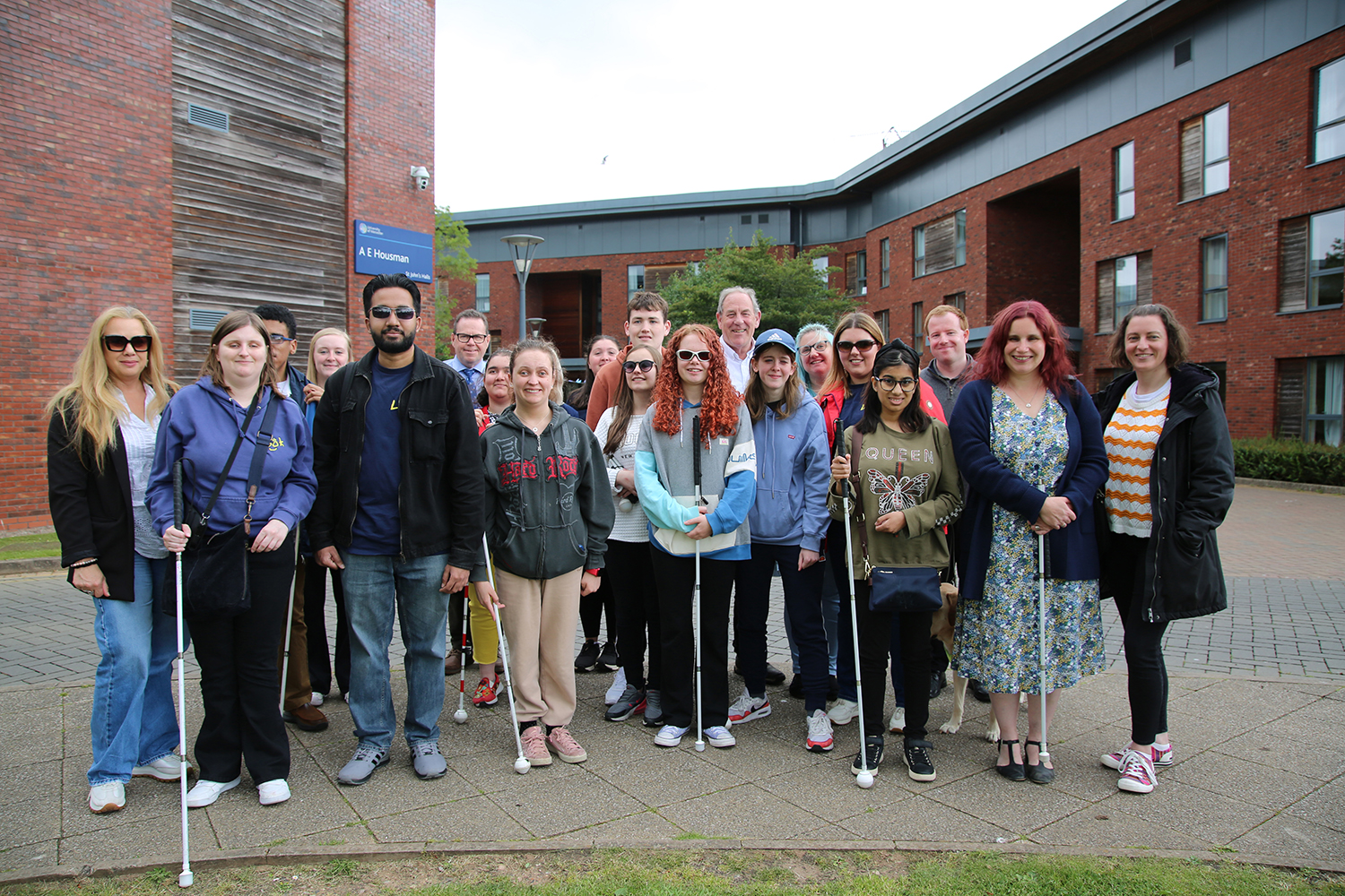 a group of staff and students standing on the university of worcester campus smiling