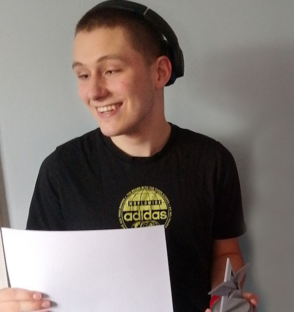 A student wearing headphones holds a certificate and an award in the shape of a star