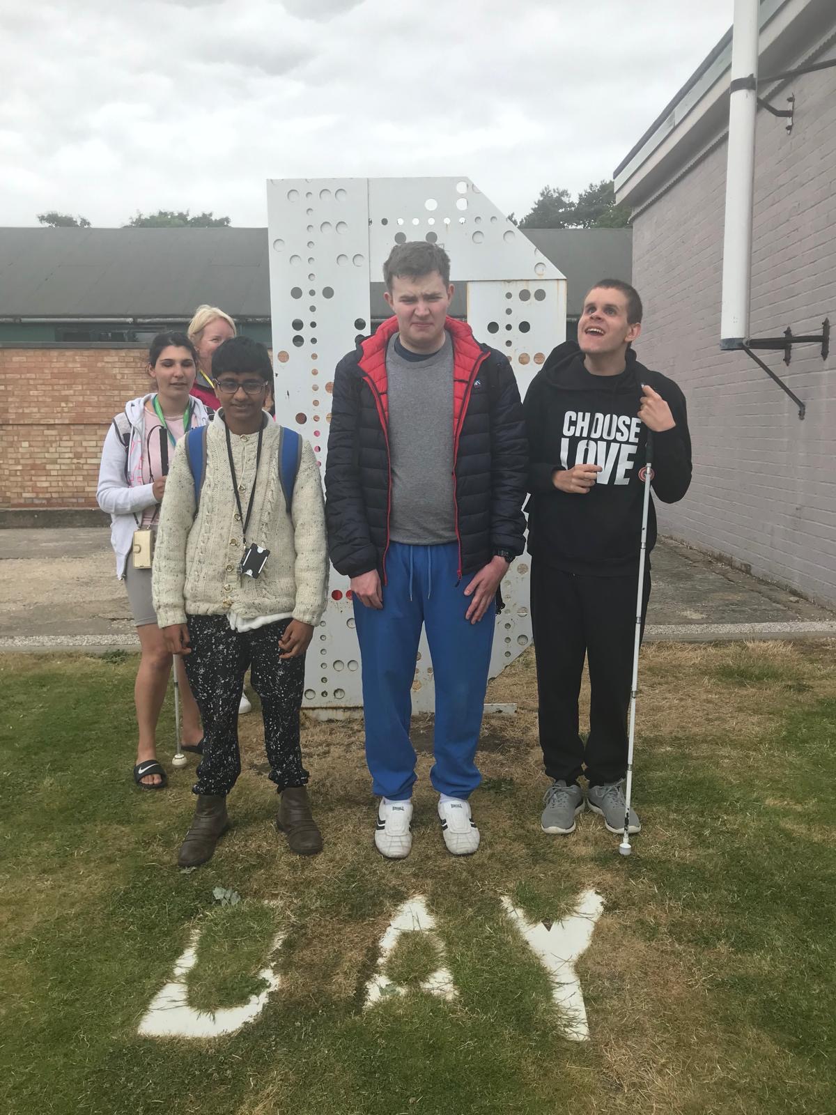 four students stand in front of a D Day memorial