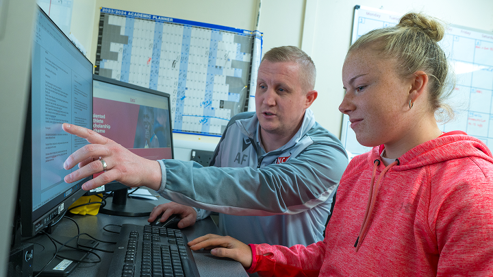 Photo of a teacher and student working at a computer.