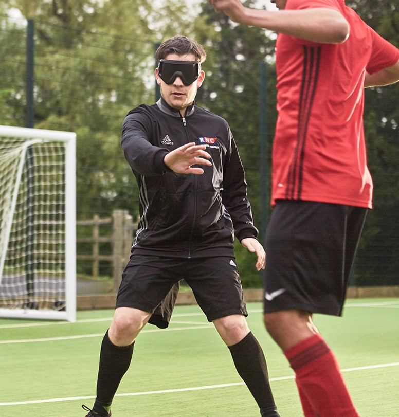 Two people playing blind football.