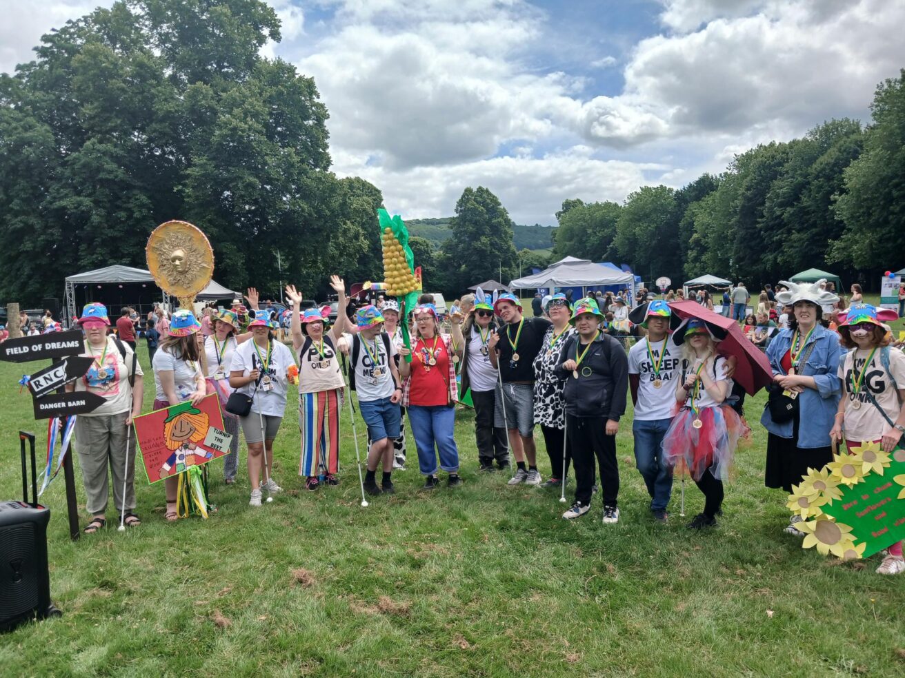 The full group in colourful hats and tshirts with animal ears, snouts and whiskers. They're all cheering and wearing their winners medals.