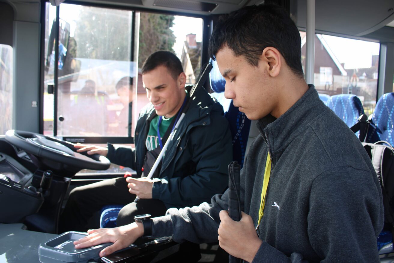 Michal in the driving seat revving the bus as Zayed explores how to pay
