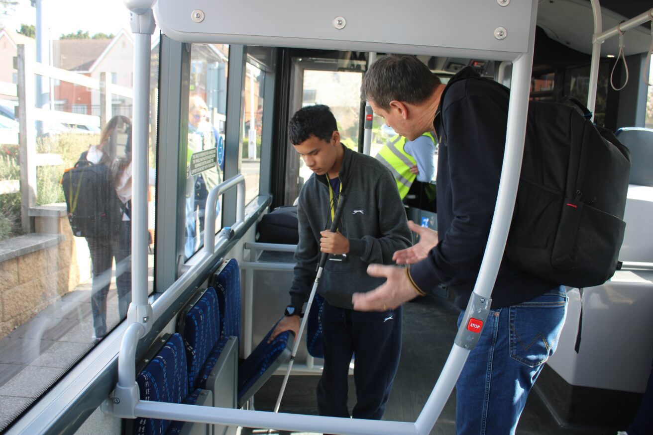Student Zayed exploring the foldaway seats with teacher Rich explaining how they work