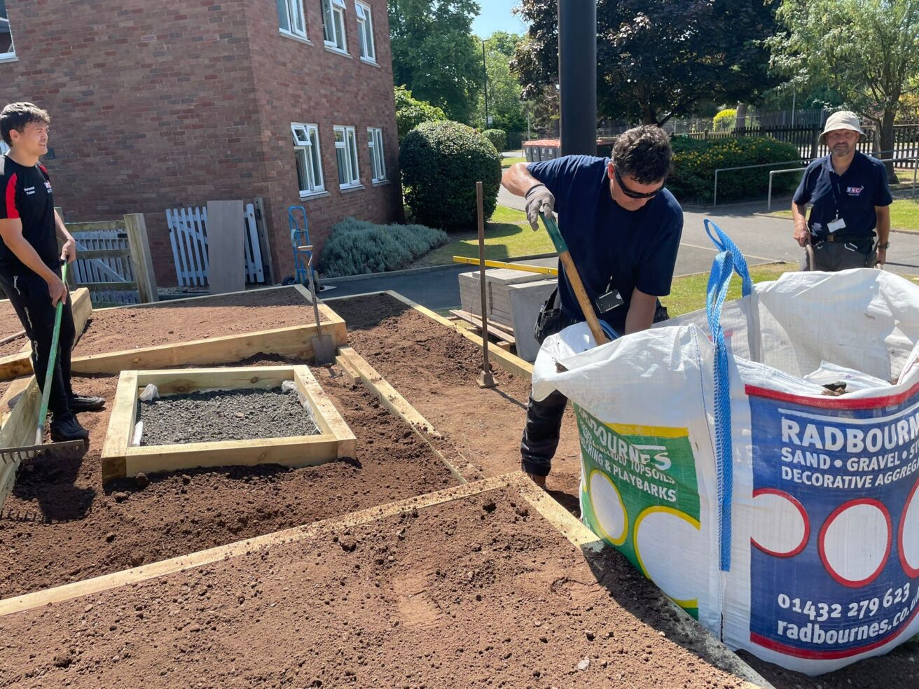 The sleepers are in and Dave and Phil are filling up the raised beds with soil, while Aaron rakes it over.