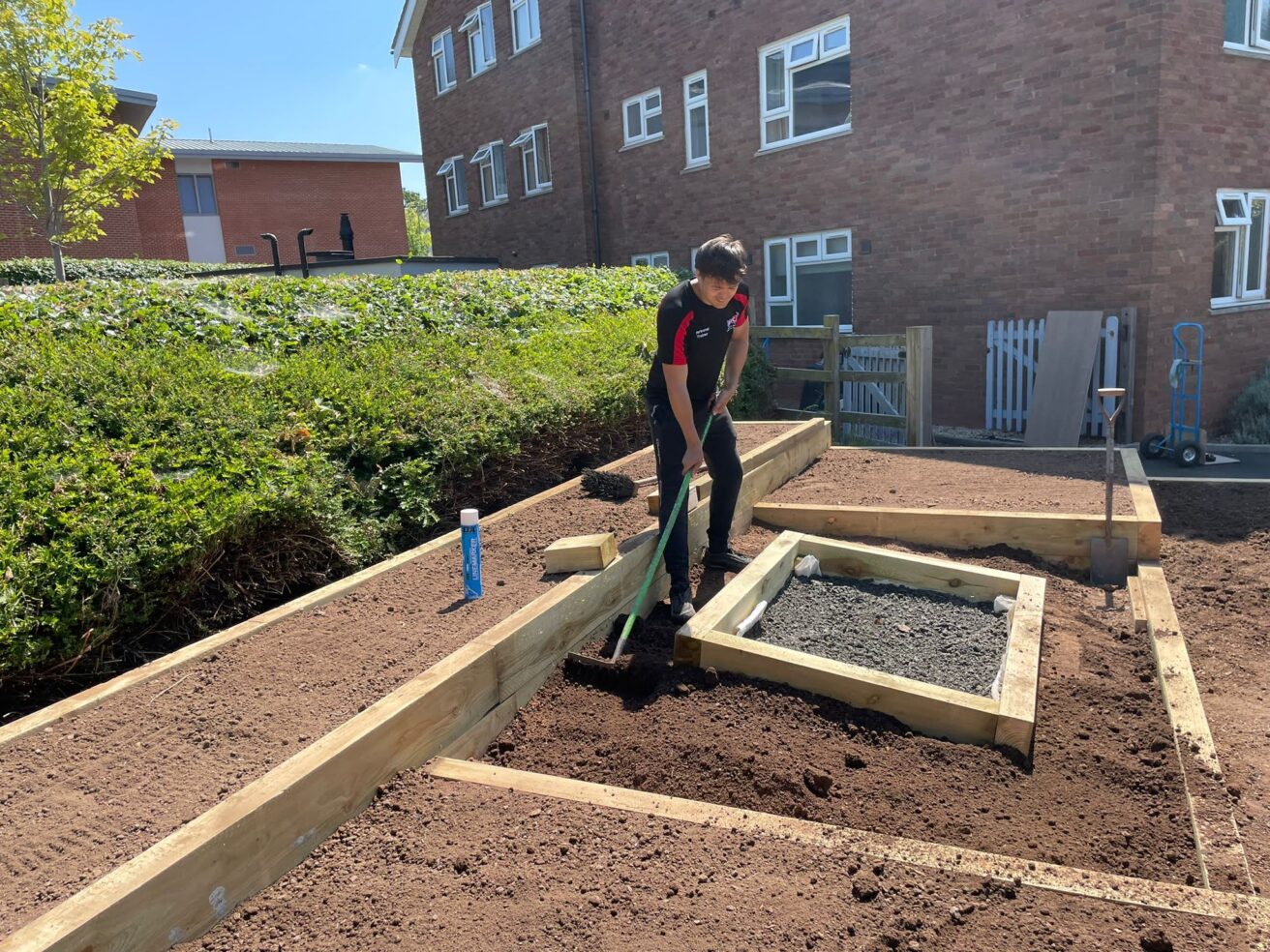 Aaron spreads the soil evenly with a rake in each of the raised beds