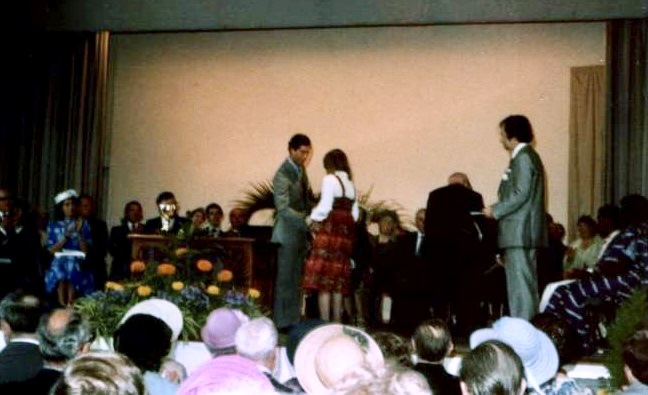 The picture below shows Alison standing on stage collecting her award from Prince Charles. There are dignitaries sat on the stage and many of the audience members in the foreground are wearing hats for the occasion.