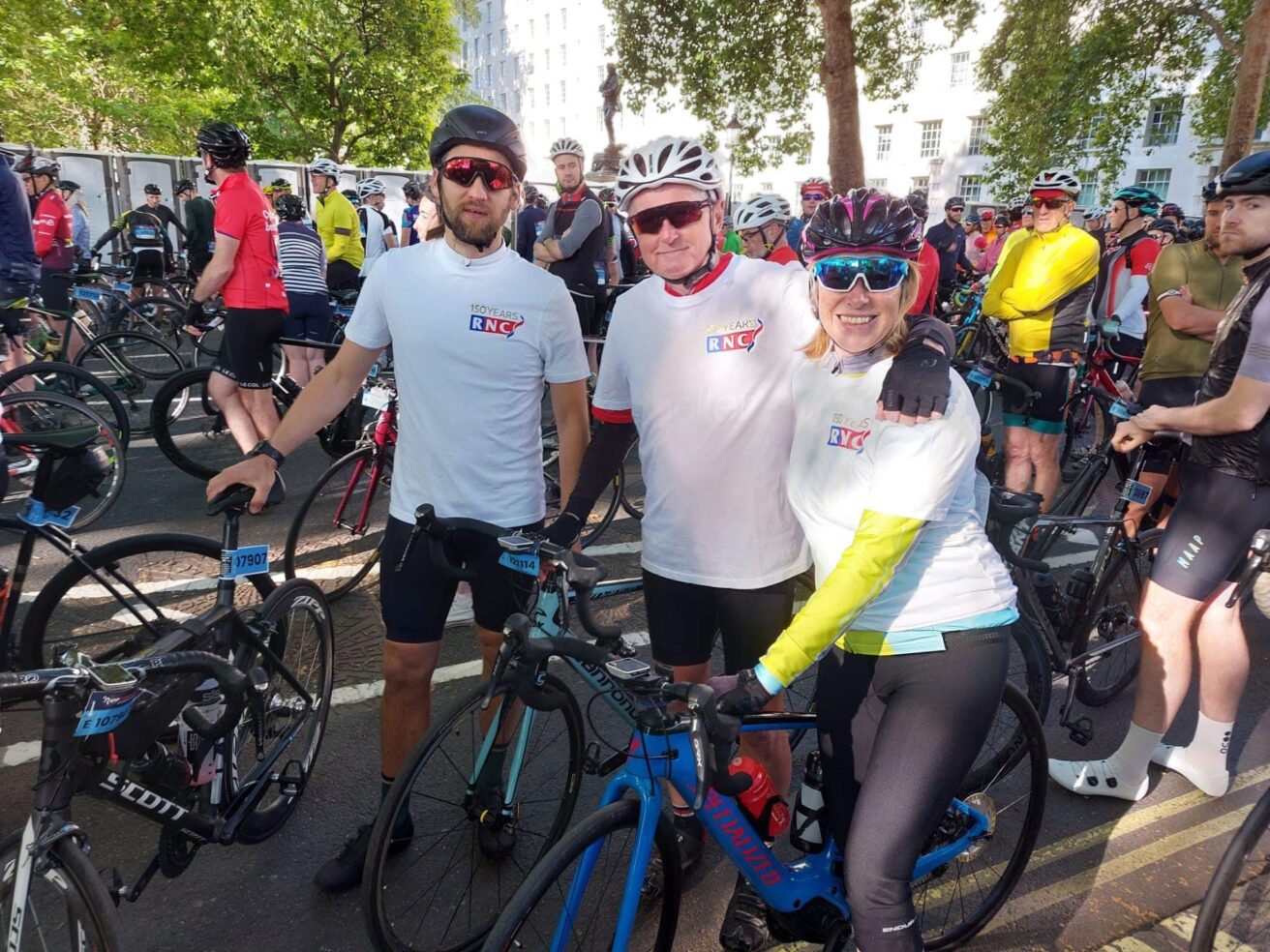 Andrew, Bill and Sheila pictured wearing white RNC t-shirts holding their bikes before the race