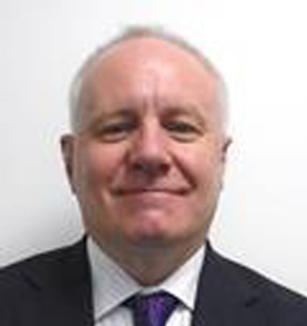 Photograph of Peter Gebbie, he has grey hair and is wearing a suit and tie.