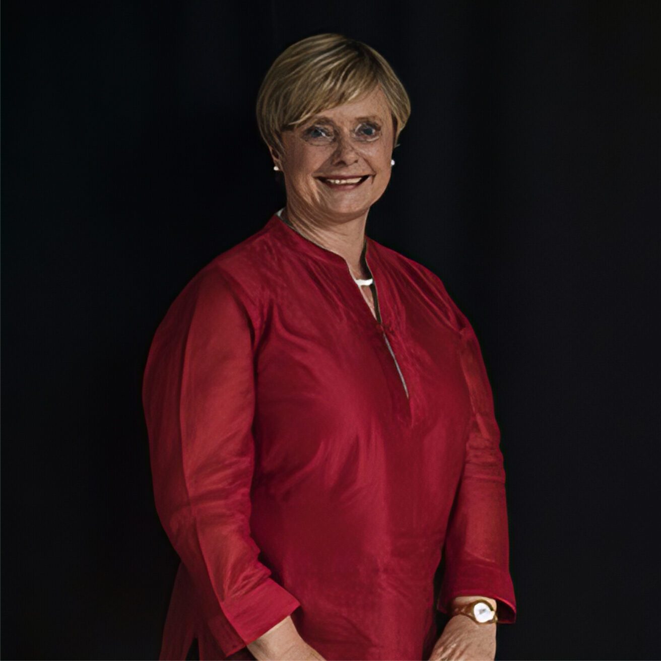 A portrait picture of Sharon Turnbull with short blonde hair smiling - she wears a satin red top