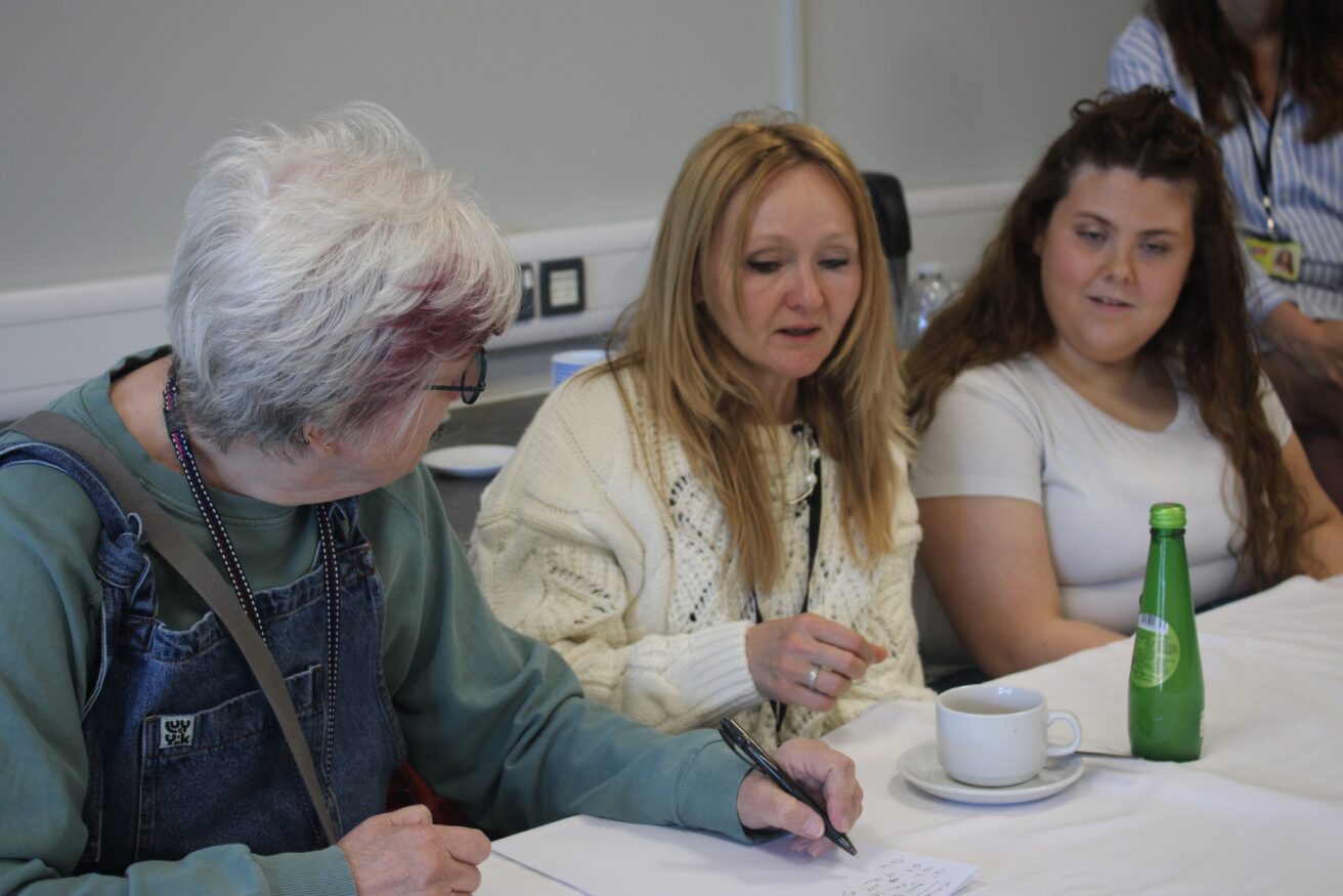 a team comprising two female volunteers and a female student sitting at a table