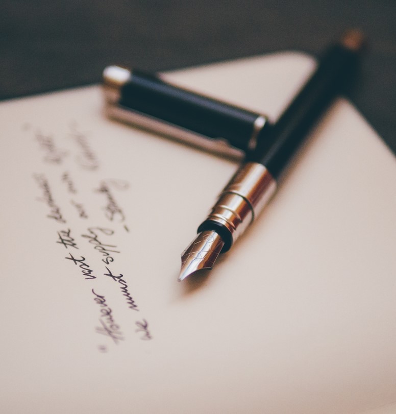 A fountain pen with its lid off lies on top of an official looking document