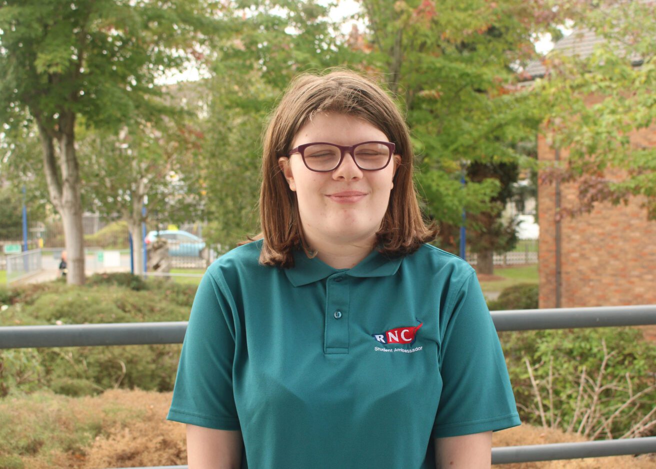 Head and shoulders portrait of Bethany wearing her dark green student ambassador polo shirt