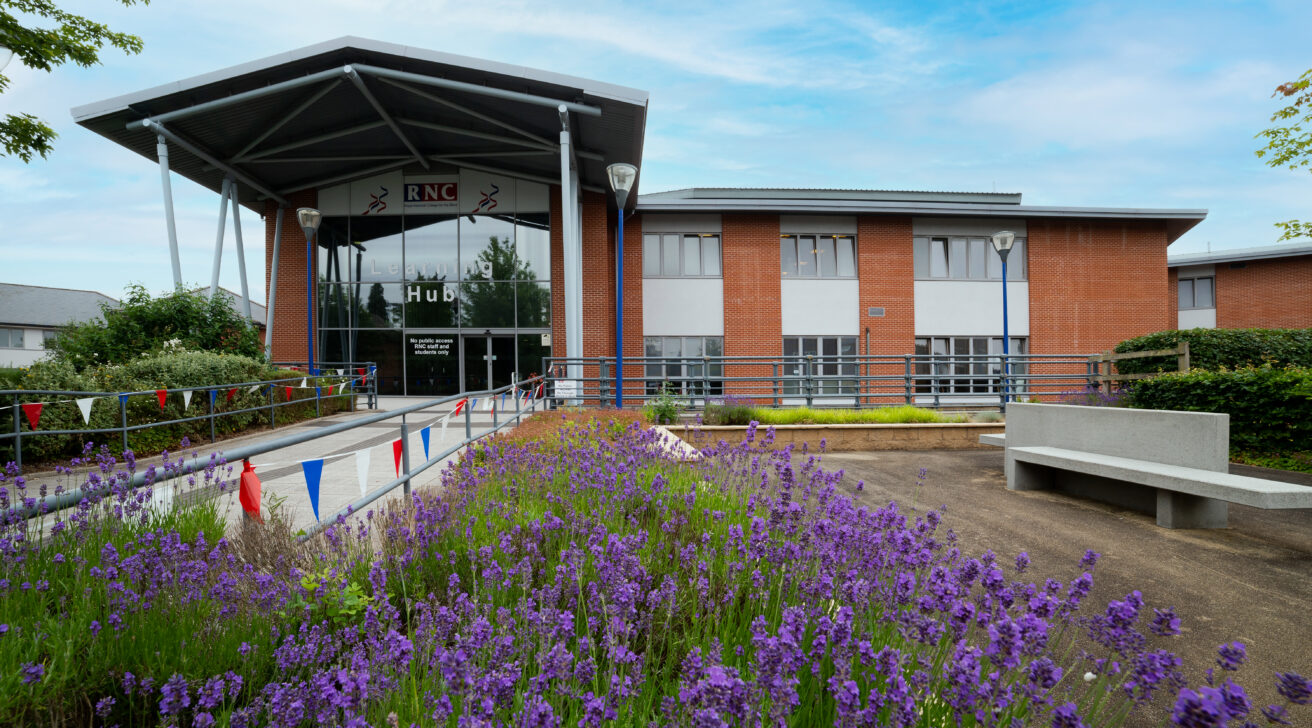 A view of the College campus with a lavender hedge in full bloom lining the ramp up to the College entrance