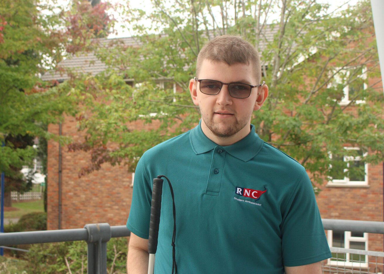 Head and shoulders portrait of Eddie wearing his dark green student ambassador polo shirt