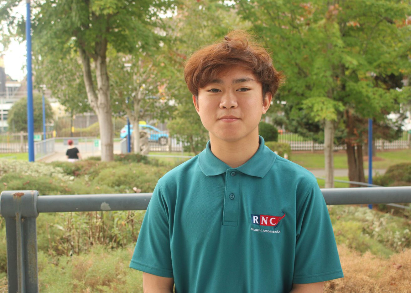 Head and shoulders portrait of Johnathan wearing his dark green student ambassador polo shirt