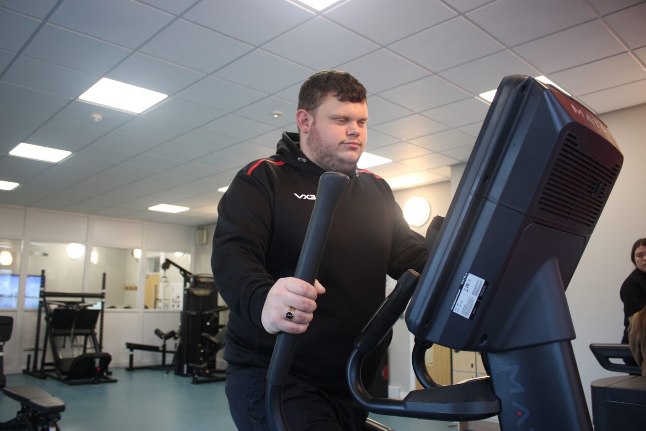 A student working out on a cross trainer in the student gym