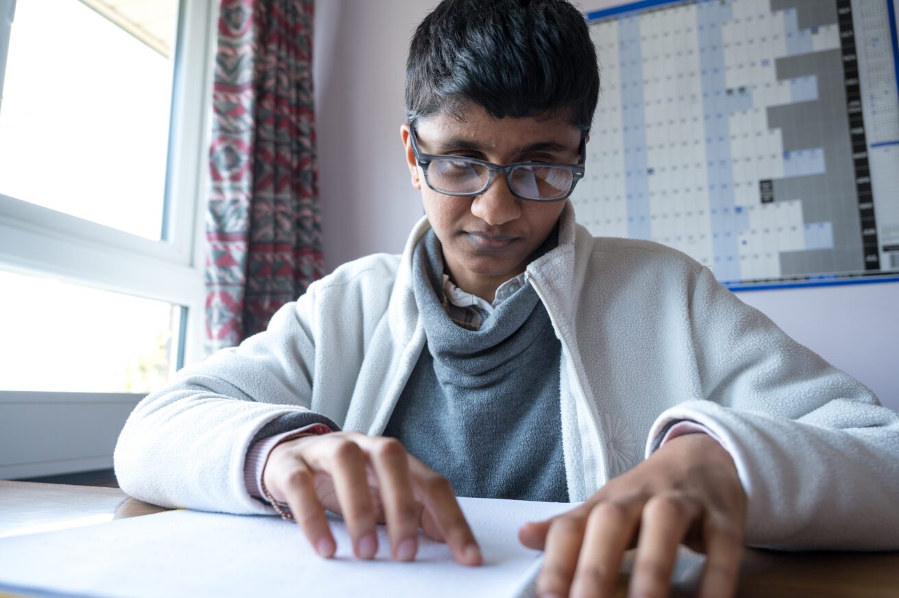 A student reading Braille using both hands