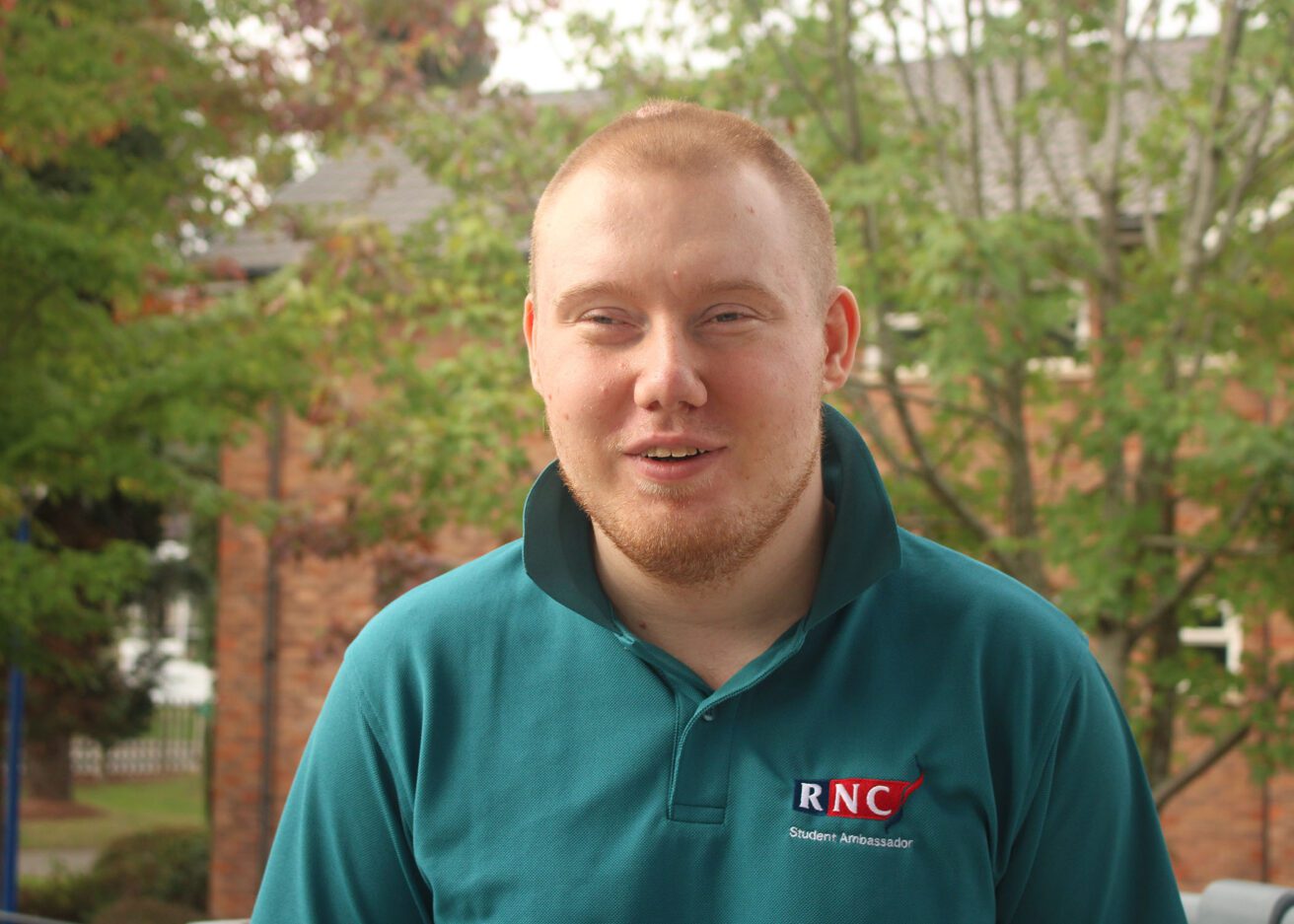 Head and shoulders portrait of Ryan wearing his dark green student ambassador polo shirt